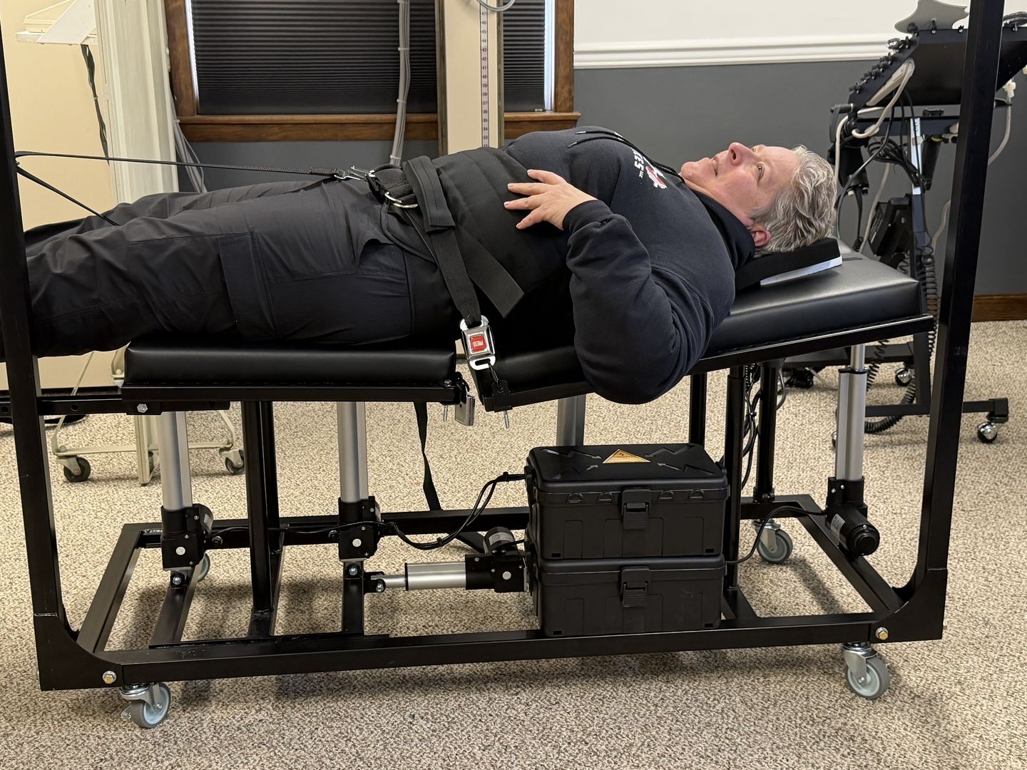 Patient positioned supine with knees supported and a pelvic harness on a motorised traction table at Optimus Spine & Posture